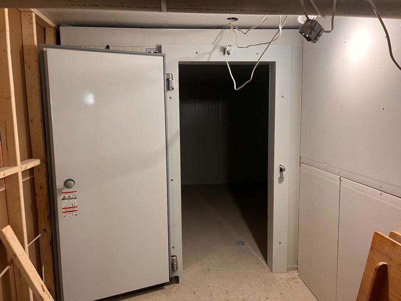 Chambre froide en panneaux isolés, porte ouverte, installée dans un local en construction