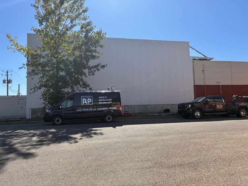 Fourgon et camion des Industries RP devant la façade en panneaux isolés terminée